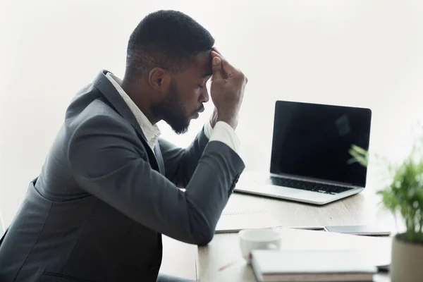 Empresario africano estresado sentado en la oficina con la mano en la frente —  Fotos de Stock