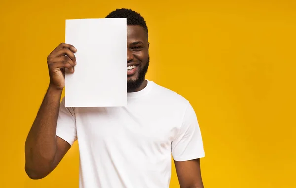 Afričan zakrývající polovinu jeho obličeje čistým papírem — Stock fotografie