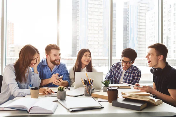 Universitaire studenten zitten samen aan tafel met boeken en laptop — Stockfoto