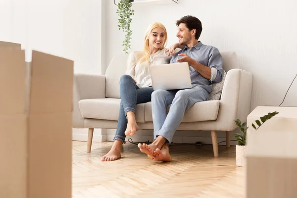 Pareja comprando muebles en línea Sentado en el sofá en nuevo apartamento — Foto de Stock