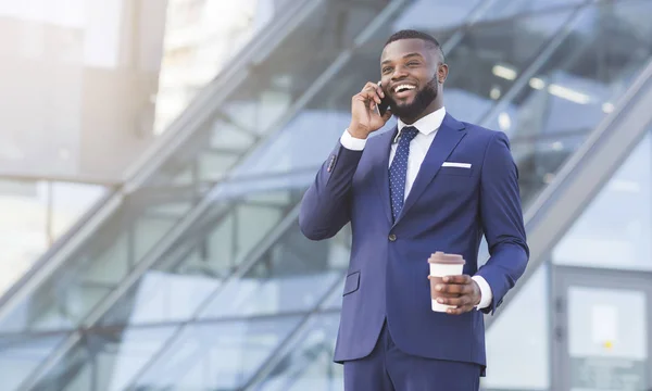 Svart affärsman talar på telefon som innehar kaffekopp i staden — Stockfoto