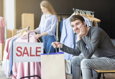 Sıkılmış erkek arkadaşı beklerken kız arkadaşı kıyafet seçerken