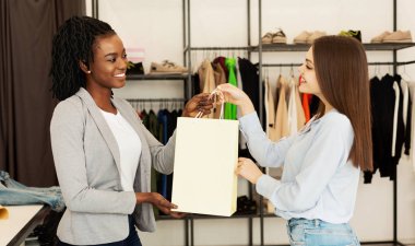 Butik alıcıya giysi li paket veren satış asistanı