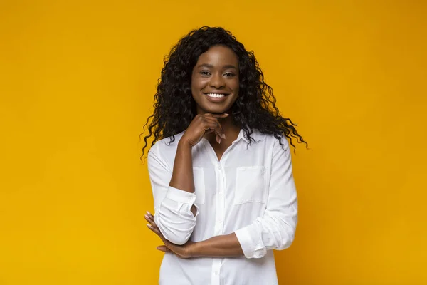 Geïnteresseerd glimlachend Afro-Amerikaanse vrouw die haar kin aanraakt — Stockfoto