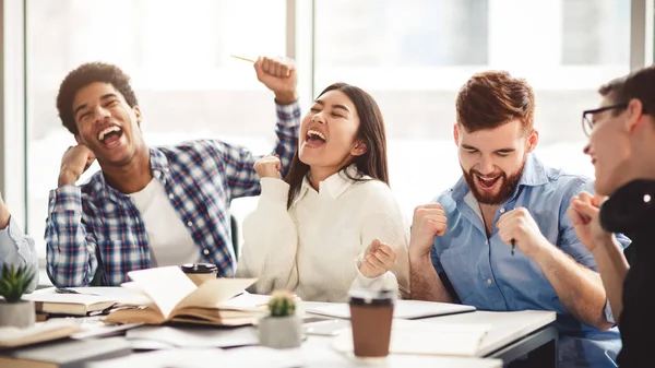 Excited students celebrating finished test in library — Stock Photo, Image