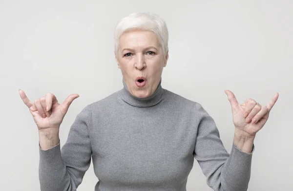 Cool granny showing modern trendy gestures on light studio background — Stock Photo, Image