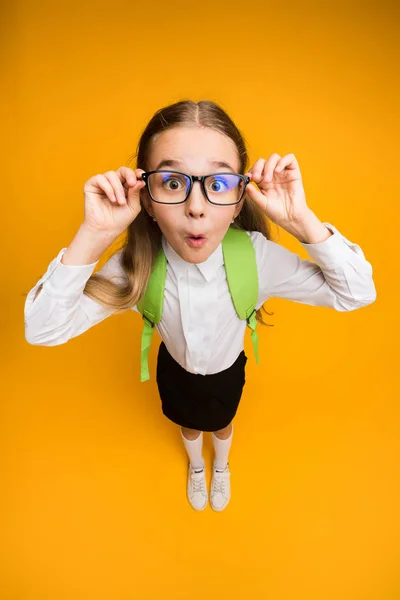 Rolig Nerdy Schoolgirl i glasögon tittar på kamera, gul bakgrund — Stockfoto