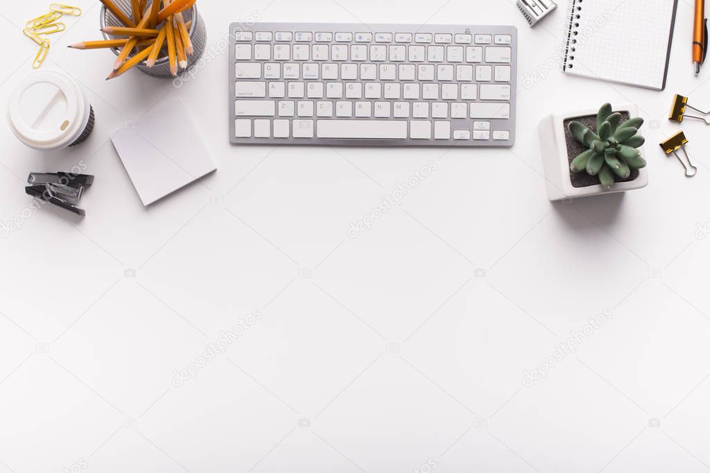 Office desk with keyboard and supplies on white table