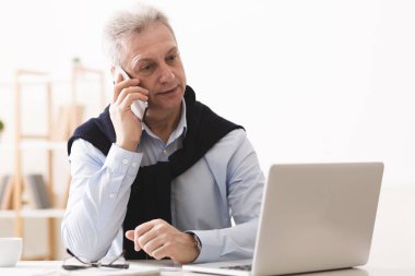 Olgun işadamı müşteri ile konuşuyor, evde çalışıyor