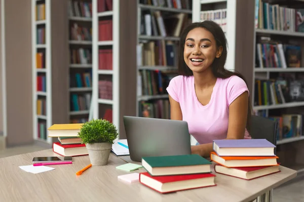 Estudante feminina alegre estudando na biblioteca da escola — Fotografia de Stock