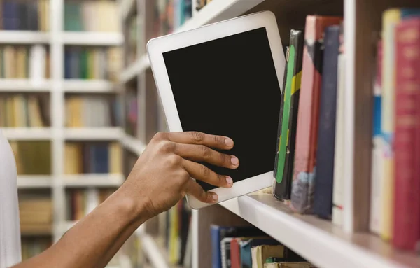 Afro estudante colocando tablet digital na estante — Fotografia de Stock