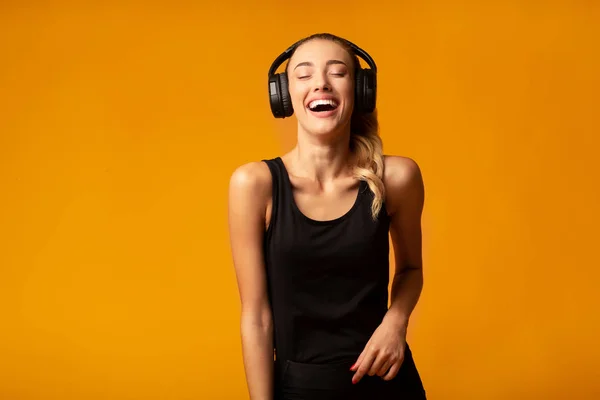 Sportovní dívka v bezdrátových sluchátkách naslouchající hudbě, žluté pozadí — Stock fotografie
