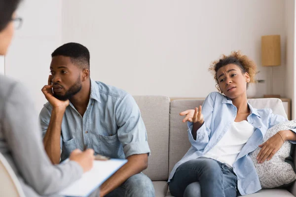 Afro esposo mirando hacia otro lado mientras esposa quejándose a consejero matrimonial —  Fotos de Stock