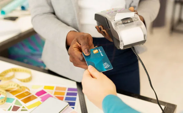 Femme assistant de magasin effectue le paiement par carte de crédit pour les vêtements de créateurs — Photo