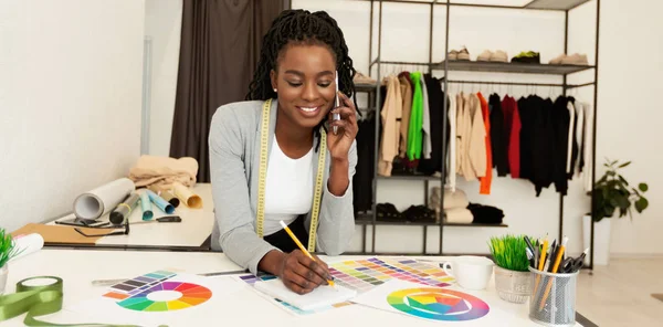 Diseñador de moda negro joven discutiendo compra con el cliente por teléfono —  Fotos de Stock