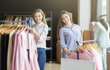 Alışveriş yapan ve kameraya gülümseyen iki neşeli kız arkadaş