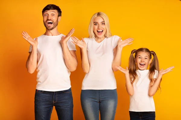 Amazed Parents And Daughter Screaming In Delight Over Yellow Background