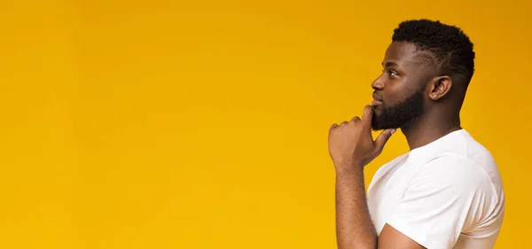 Portrait of thoughtful african american guy on yellow background — Stock Photo, Image