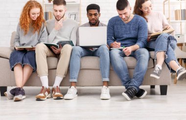 Sınavlara birlikte hazırlanan öğrenciler, dizüstü bilgisayar ve kitap kullanarak