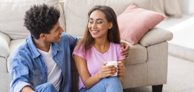 Gençler konuşuyor ve kahve içiyor, evde yerde oturuyor