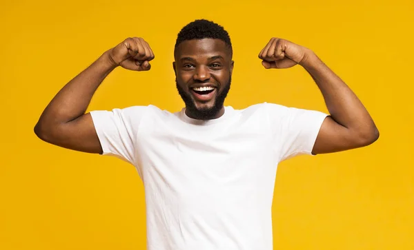 Afričan americký se usmívá a ukazoval na kameru biceps — Stock fotografie