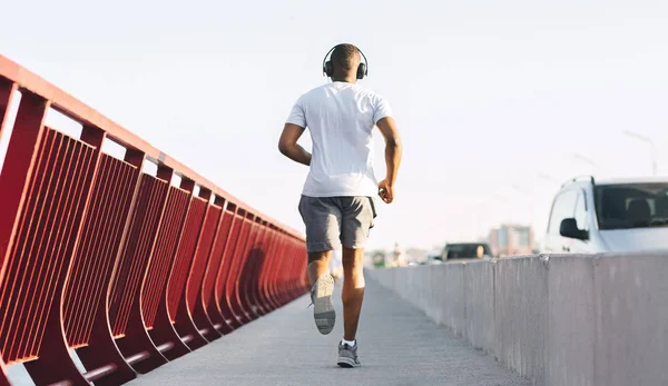 Sporty african american guy running along the bridge — Stock Photo, Image