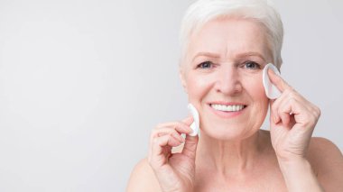 Sevimli yaşlı kadın pamuk pedleri ile yüzünü temizlik