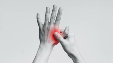 Genç adam acı lı eline masaj yapıyor, siyah beyaz