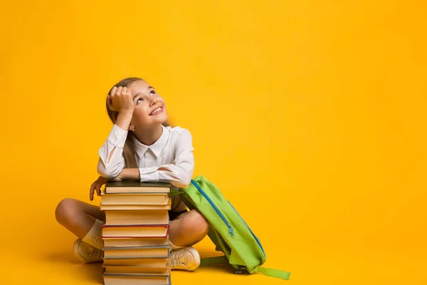 Menina bonito sonhando sobre a escola sentado com mochila e livros — Fotografia de Stock