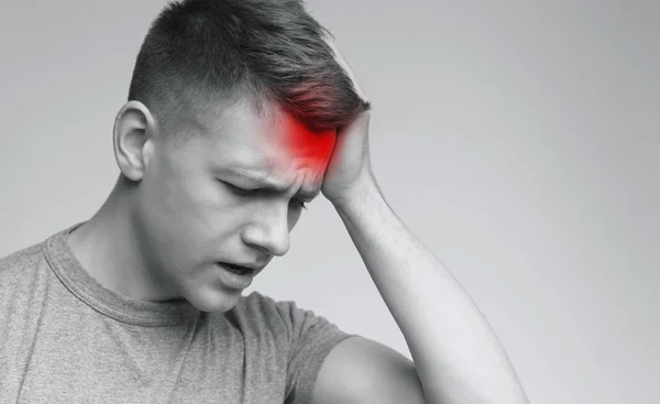 Frustrierter junger Mann berührt seinen Kopf mit der Hand — Stockfoto