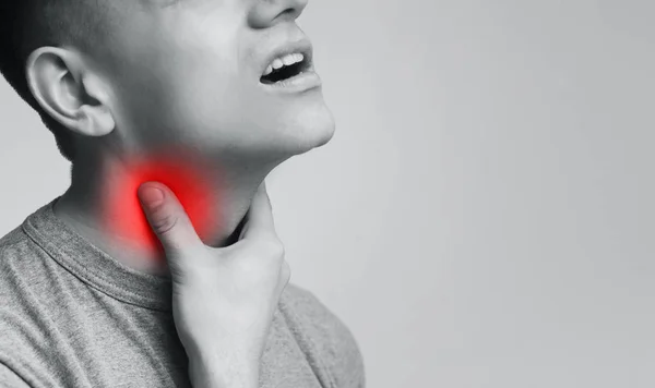 Giovane uomo che soffre di dolore alla gola, toccando il collo infiammato — Foto Stock