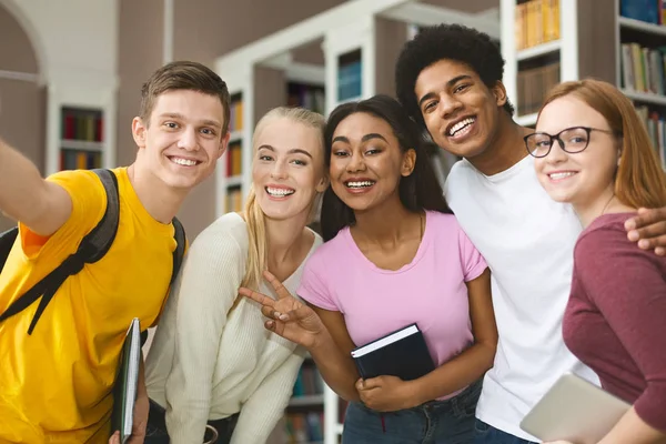 Mutlu uluslararası üniversite öğrencileri kütüphanede selfie çekiyor