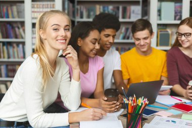 Kütüphanede birlikte okuyan neşeli üniversite öğrencileri