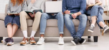 Sınıf arkadaşları birlikte çalışıyor, dizüstü bilgisayar ve kitap kullanıyor