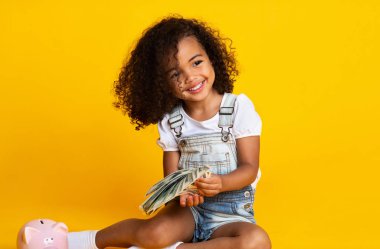 Sevimli afro kız para demet tutan, sarı arka plan