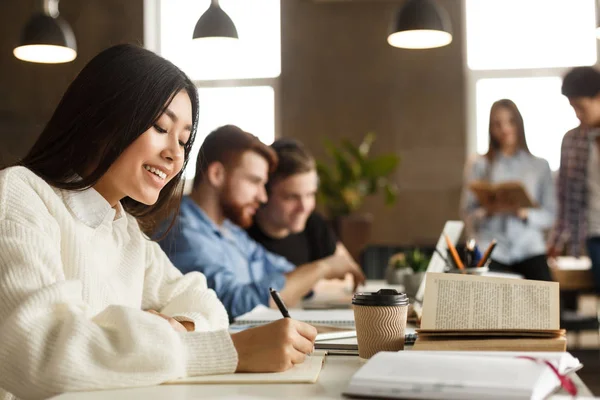 Asiatisches Mädchen bereitet sich auf Vorlesungen vor, macht Notizen in der Bibliothek — Stockfoto