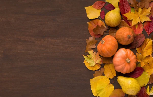 Herbstlaub mit drei dekorativen Kürbissen auf Holz — Stockfoto