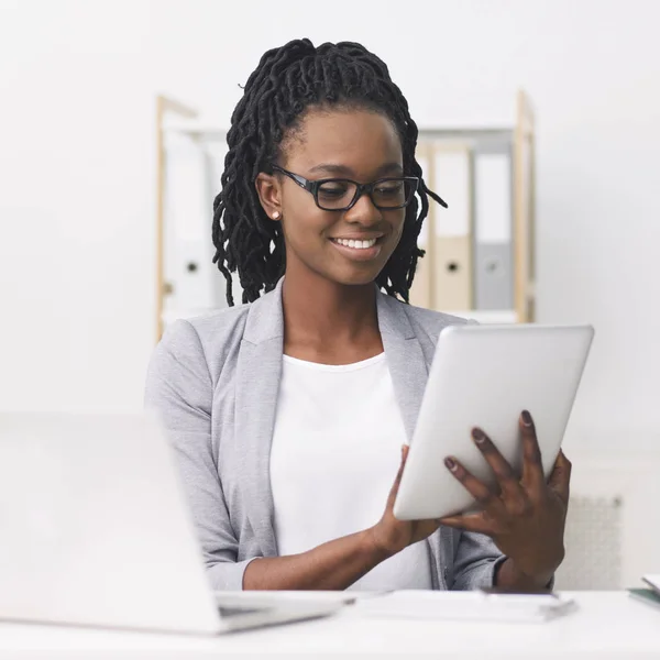 Ragazza d'affari afro-americana che utilizza tablet e laptop in ufficio — Foto Stock