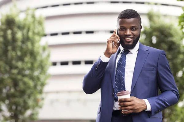 Afro affärsman som har kaffe och pratar på mobiltelefon utomhus — Stockfoto