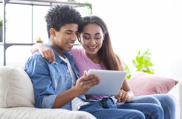 Adolescentes alegres usando tablet digital juntos enquanto sentados em casa — Fotografia de Stock