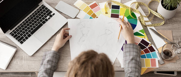 Платье рисует эскизы, проектирует новую коллекцию. вид сверху
