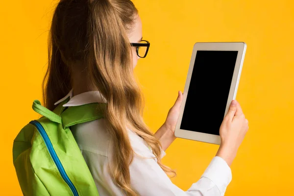 空白のタブレット画面を見て小学生の女の子, 黄色の背景 — ストック写真