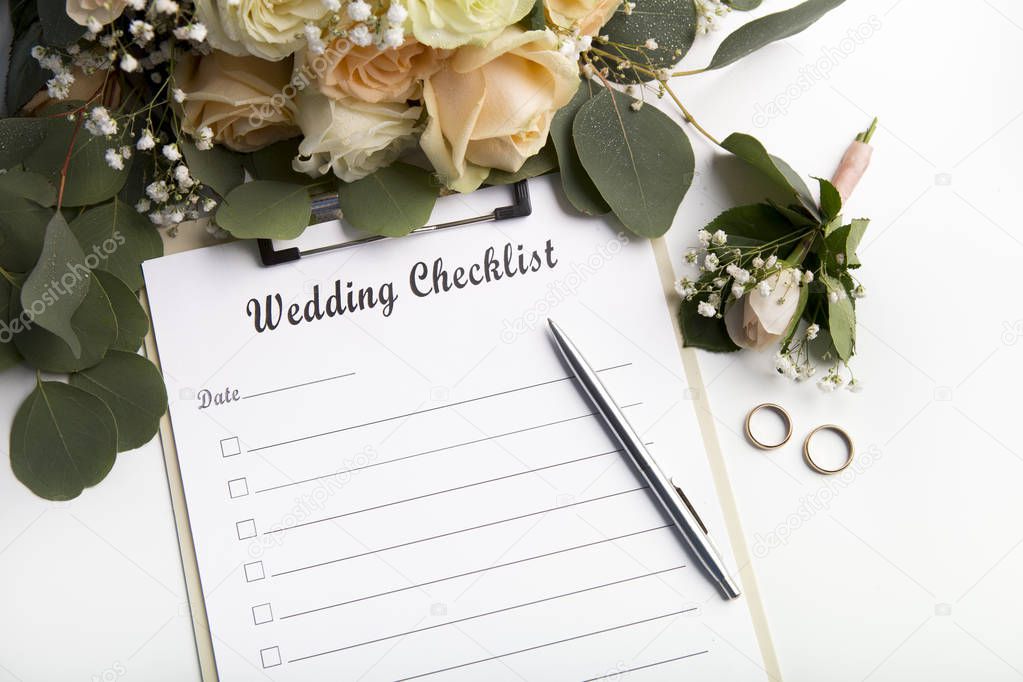 Planning checklist with pen for writing, golden rings and roses