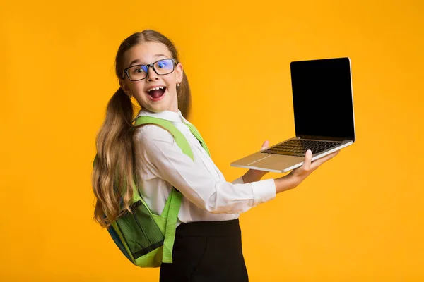 Happy Schoolgirl Holding Laptop With Blank Screen On Yellow Background — Stock Photo, Image