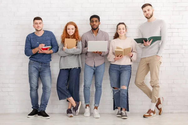 Groupe d'amis divers posant avec des gadgets et des livres — Photo