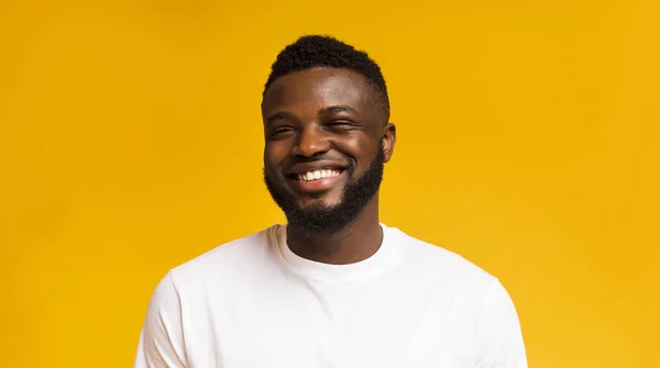 Bonito despreocupado preto cara rindo no amarelo estúdio fundo — Fotografia de Stock