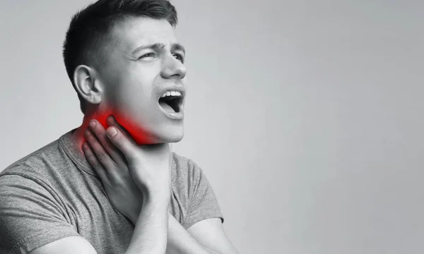 若い男が首の痛みに触れ、不快な痛みを伴う感情 — ストック写真