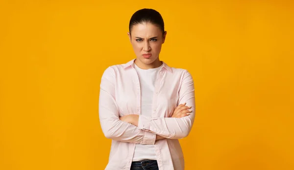 Irritado jovem mulher franzindo as mãos cruzando em fundo amarelo — Fotografia de Stock