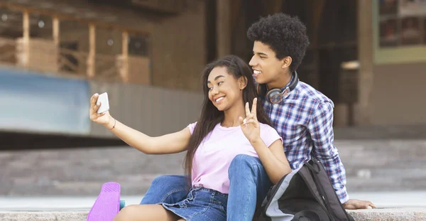 Pareja joven sonriendo y tomando selfie al aire libre — Foto de Stock