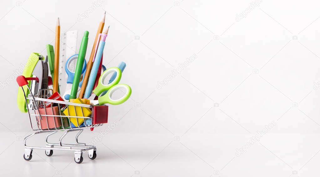 Shopping cart with office stationery isolated on white